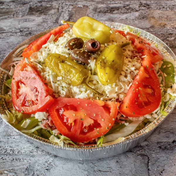 Stavro's Pizza House IV Greek salad with tomatoes, peppers, olives, and feta cheese in a foil container.